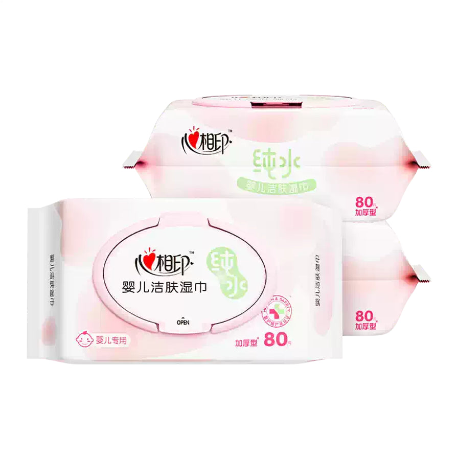 两包心相印婴儿洁肤湿巾叠放展示，突出显示带盖包装和80抽加厚型规格，黑色背景。