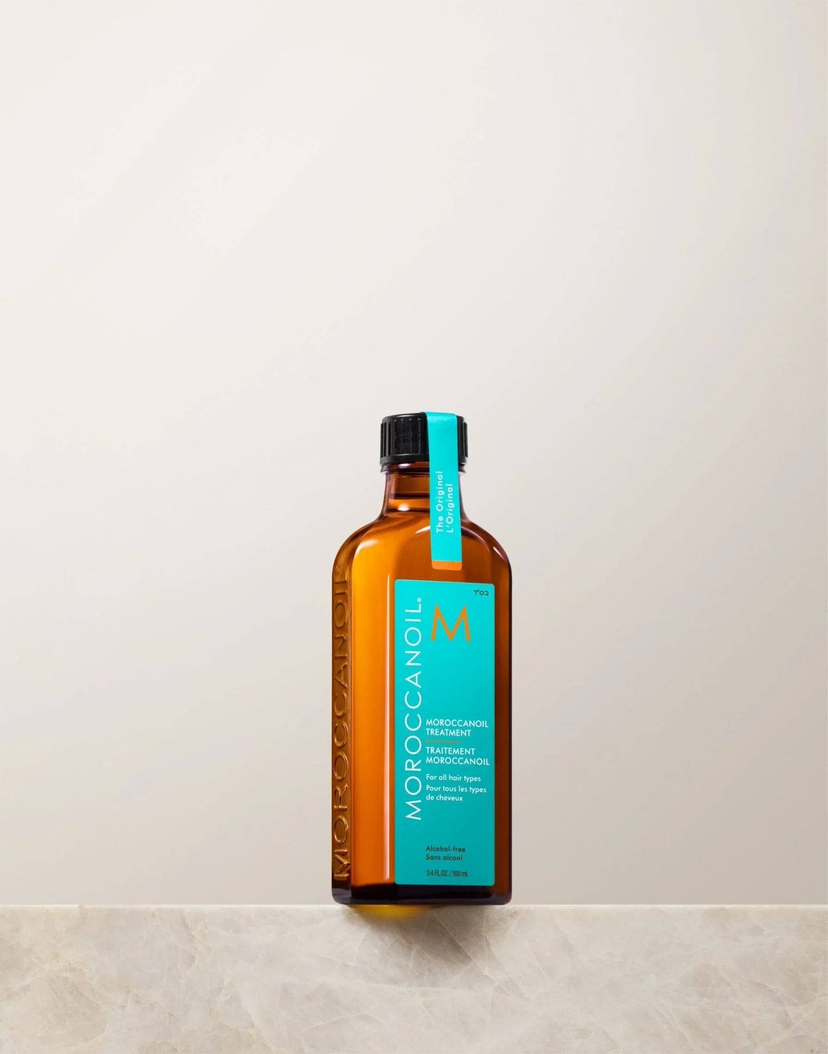 Moroccanoil 摩洛哥护发精油置于大理石台面上，展示产品整体外观与质感。