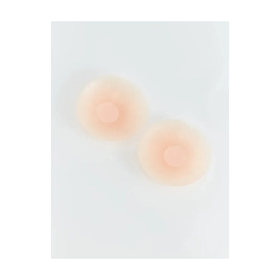 白色背景上展示的一对肤色圆形隐形乳贴，表面光滑无包装。