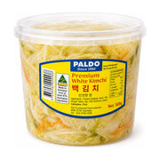 Paldo 品牌 500g 桶装白泡菜，透明塑料桶身可见内部浅色爽脆泡菜，黄色标签印有 Premium White Kimchi 字样。
