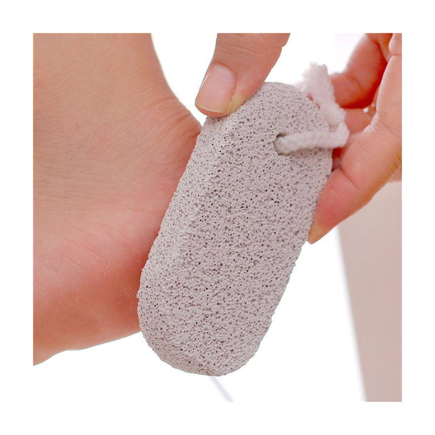 手持天然磨脚石正在打磨脚后跟死皮的特写镜头，展示足部护理使用场景。