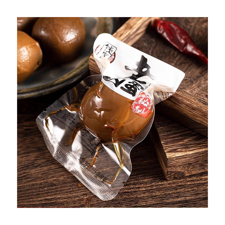 钱家香老卤鸡蛋的独立真空小包装，背景为木质托盘与干辣椒，展示即食便携特点。