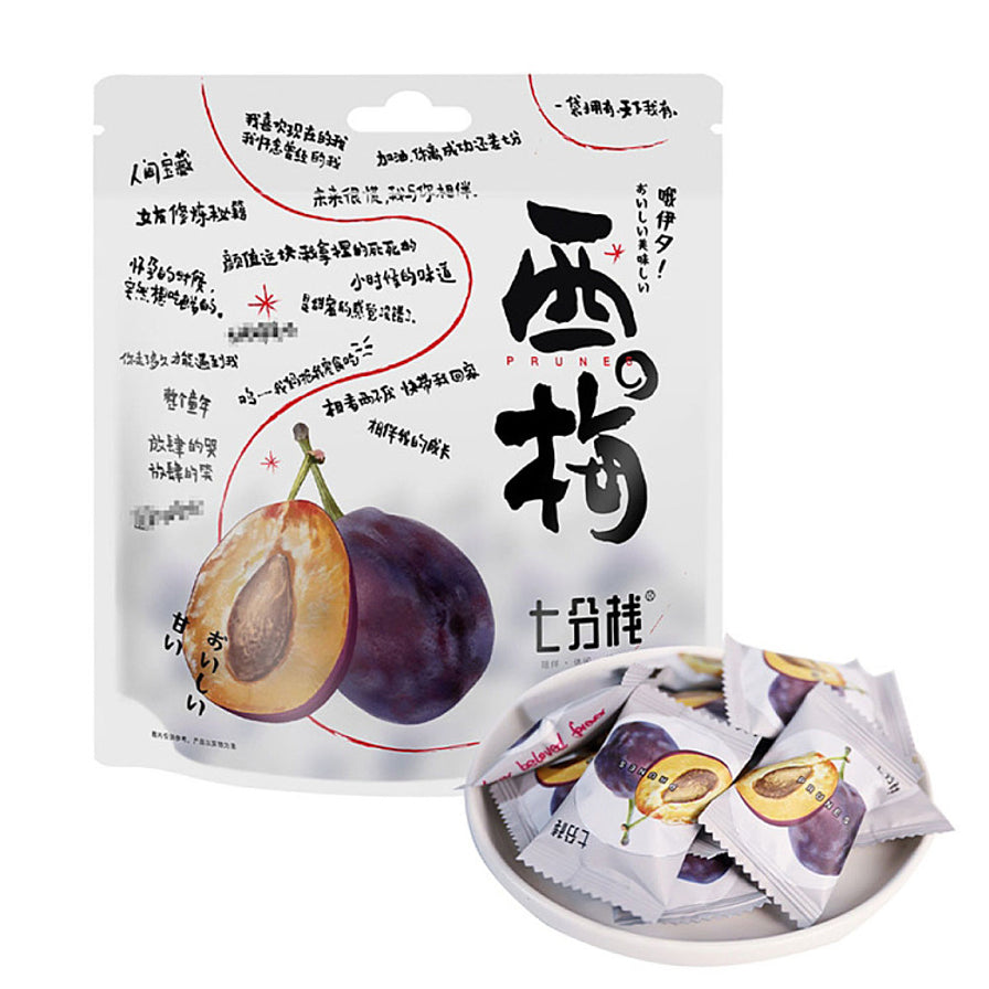 七分栈西梅大包装袋，前方白色小碟中装有多个独立包装的西梅果干，包装袋上印有西梅剖面图。