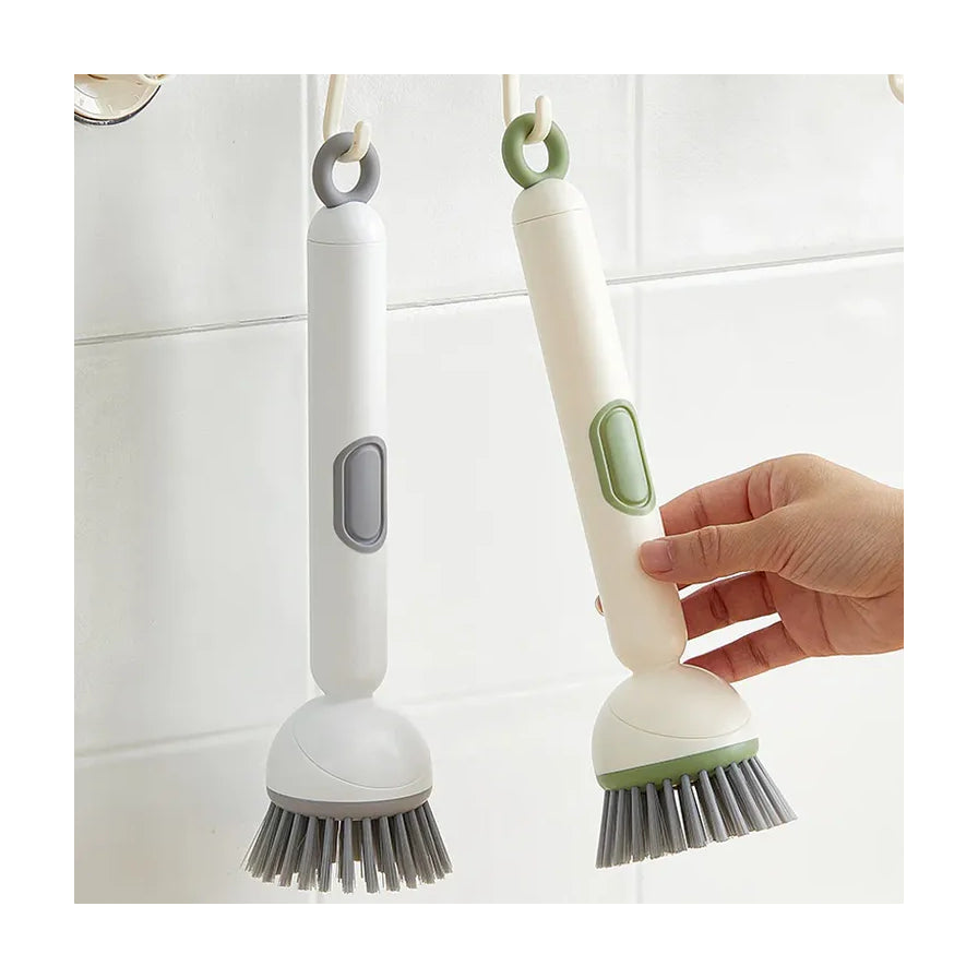 手部拿取挂在墙上的绿色长手柄锅刷，旁边挂着同款白色锅刷，展示收纳挂孔功能。