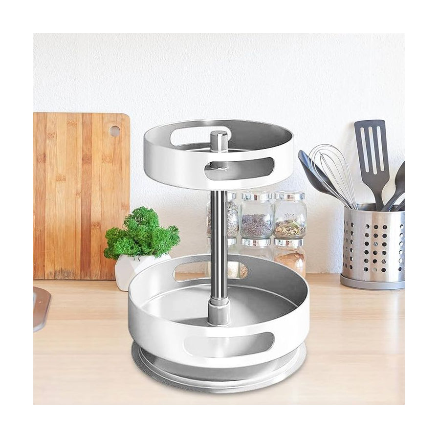 白色双层旋转调料架放置在木质厨房台面上，背景可见砧板、绿植盆栽及不锈钢餐具筒，展示实际使用场景。
