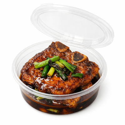 透明圆盒装葱烧大排成品图，带骨猪排裹满浓油赤酱并点缀葱段