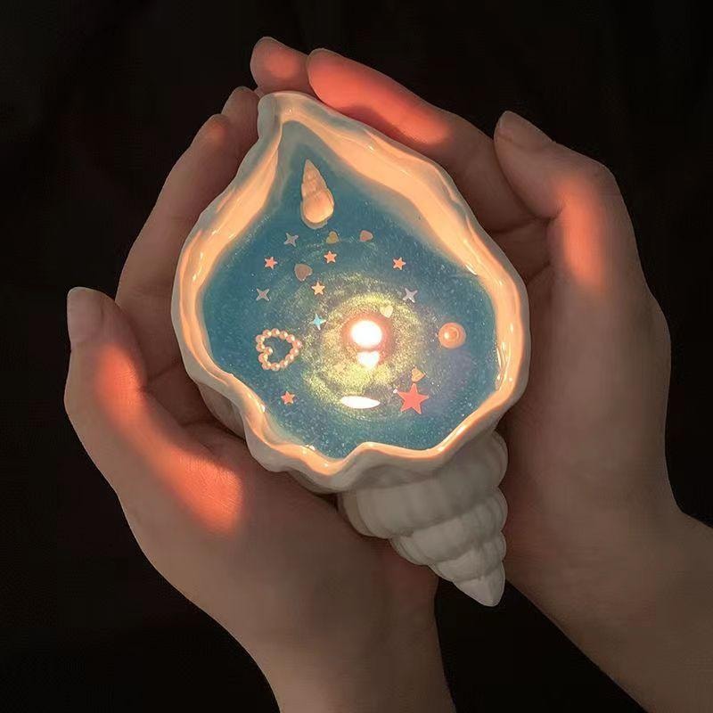 海螺星空香薰蜡烛细节特写，展示烛光下的星空质感与柔和氛围。