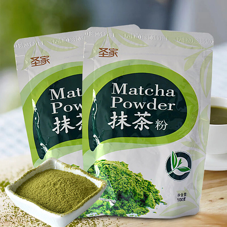 两袋圣家抹茶粉并排摆放，左下角有一小碗抹茶粉，背景可见一杯冲泡好的抹茶饮品。