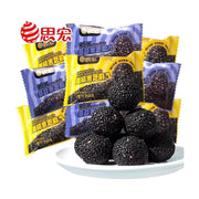 思宏桑葚黑芝麻丸，白色圆盘中盛放着多颗圆润饱满的黑芝麻丸，背景为蓝黄相间的独立小包装袋，包装上印有品牌Logo及产品名称。