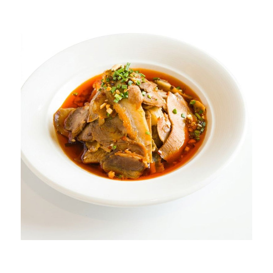 白瓷盘中盛放的夫妻肺片，红油色泽诱人，肉片层叠并撒有葱花点缀，背景为纯白色。