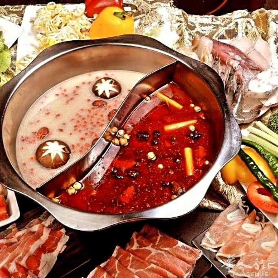 摆满肉片和蔬菜的餐桌上，正在沸腾的不锈钢鸳鸯火锅，展示家庭聚餐使用场景。