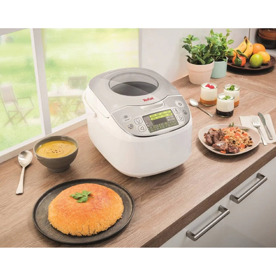 摆放在厨房台面上的 Tefal 电饭煲，周围配有米饭、炖汤、甜点等各式料理，展示其多功能用途。