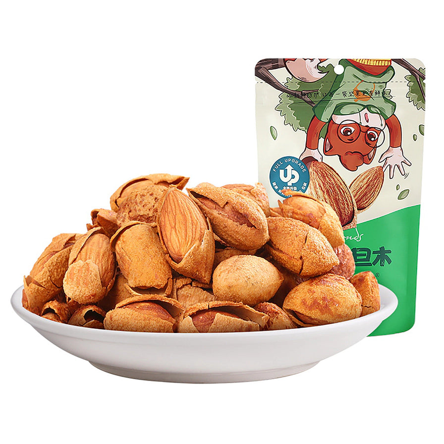 三只松鼠手剥巴旦木，白色瓷盘中堆叠着外壳微开、果仁饱满的巴旦木，背景为绿色大头装包装袋。