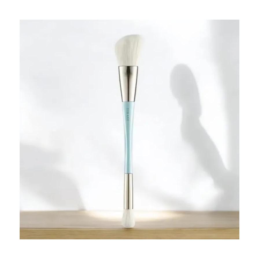 彩棠双头化妆刷竖立在木质桌面上，背景有柔和的光影投射。