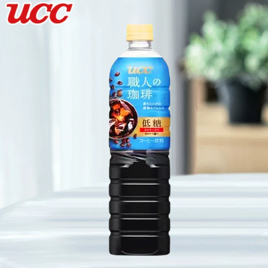 单瓶展示的UCC职人咖啡低糖美式咖啡，蓝色标签包装，背景带有模糊的居家绿植环境，左上角有UCC品牌标志。