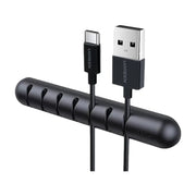 UGREEN 黑色桌面理线器特写，展示 7 个独立卡槽收纳 USB - C 和 USB - A 数据线，白色背景。