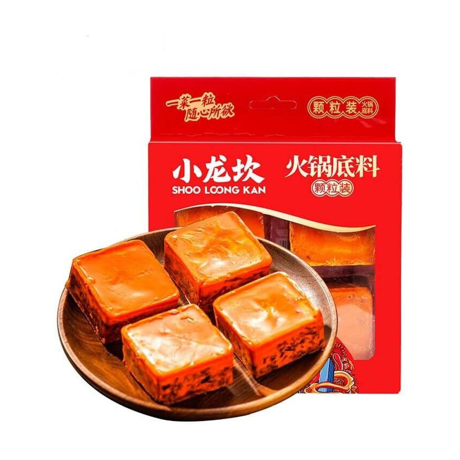 小龙坎牛油火锅底料四粒装红色包装盒，前景木盘上摆放着四块方形独立包装的橙色牛油底料颗粒。
