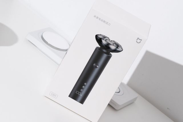 小米米家 S301 电动剃须刀白色包装盒与充电底座的产品摄影图。