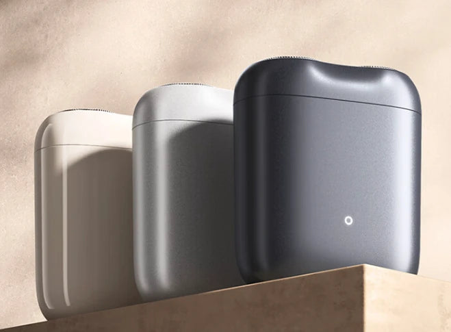 米家智能感应剃须刀三种不同颜色的产品并排展示，包括米白、银灰和深蓝色，背景为暖色调光影。