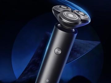 小米米家 S301 电动剃须刀特写，展示蓝色光效下的三头旋转刀网细节。