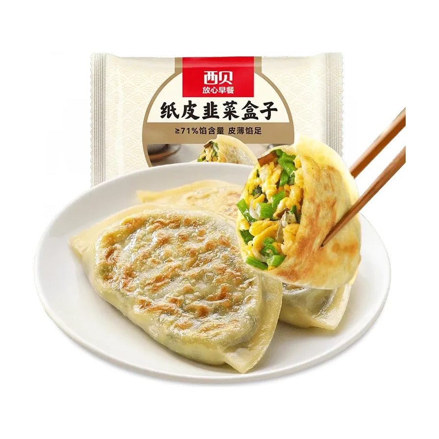 西贝纸皮韭菜盒子包装及盘中展示，皮薄透亮，内馅可见饱满的韭菜和鸡蛋，筷子夹起展示横截面。