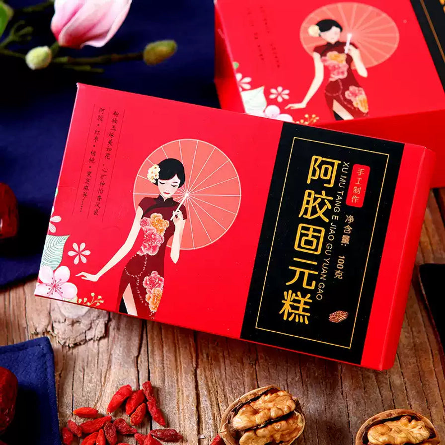 序木堂阿胶固元膏包装盒斜侧视角，背景配有核桃、红枣等原材料。