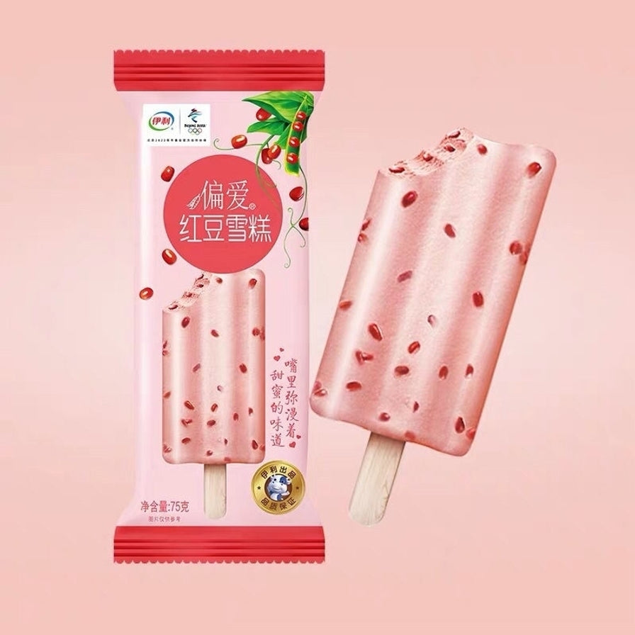 伊利偏爱红豆雪糕包装及一支咬开后的红豆雪糕，展示内部饱满的红豆颗粒，粉色背景。