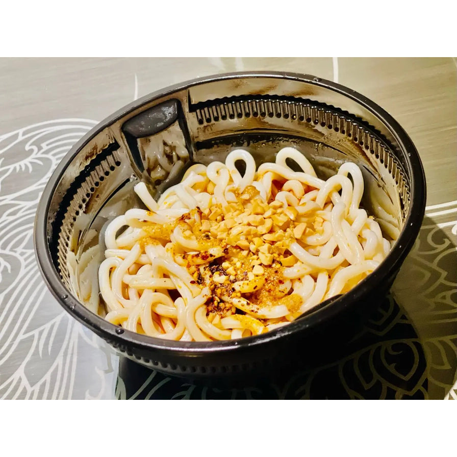 搅拌均匀后的袁鲜甜水面，粗面条裹满红油酱汁并撒有香脆花生碎，盛放在黑色碗中。