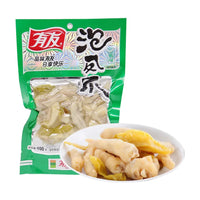 有友泡椒凤爪绿色包装袋，前方白色圆盘盛放着去骨凤爪和黄色泡椒，展示产品实物。