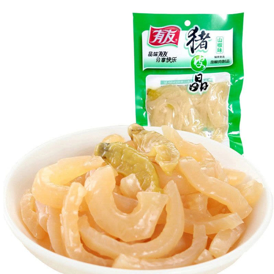 一碗盛满的透明脆爽猪皮晶，背景为有友山椒味猪皮晶的绿色包装袋。
