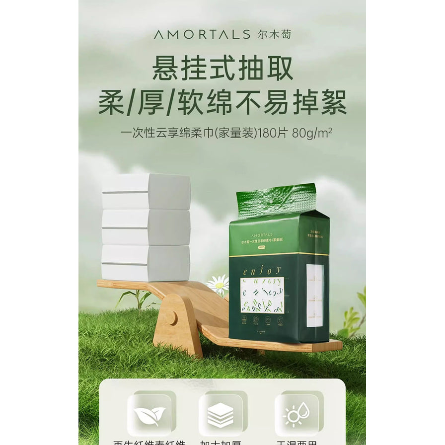 尔木萄一次性云享棉柔巾在木质跷跷板上的展示，左侧堆叠多层洗脸巾，右侧为绿色包装袋，上方配有悬挂式抽取和不易掉絮的文字介绍。
