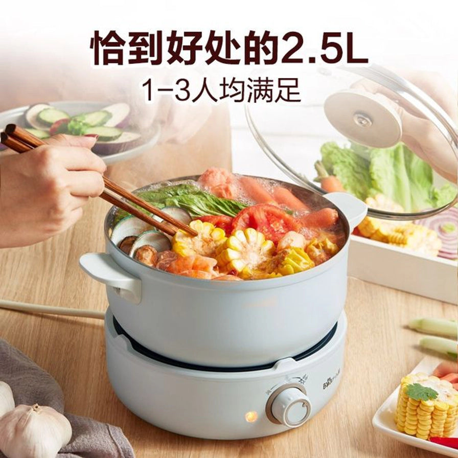 小熊电煮锅2.5L容量展示，正在煮火锅，配有透明锅盖和木质餐具，适合1 - 3人使用。