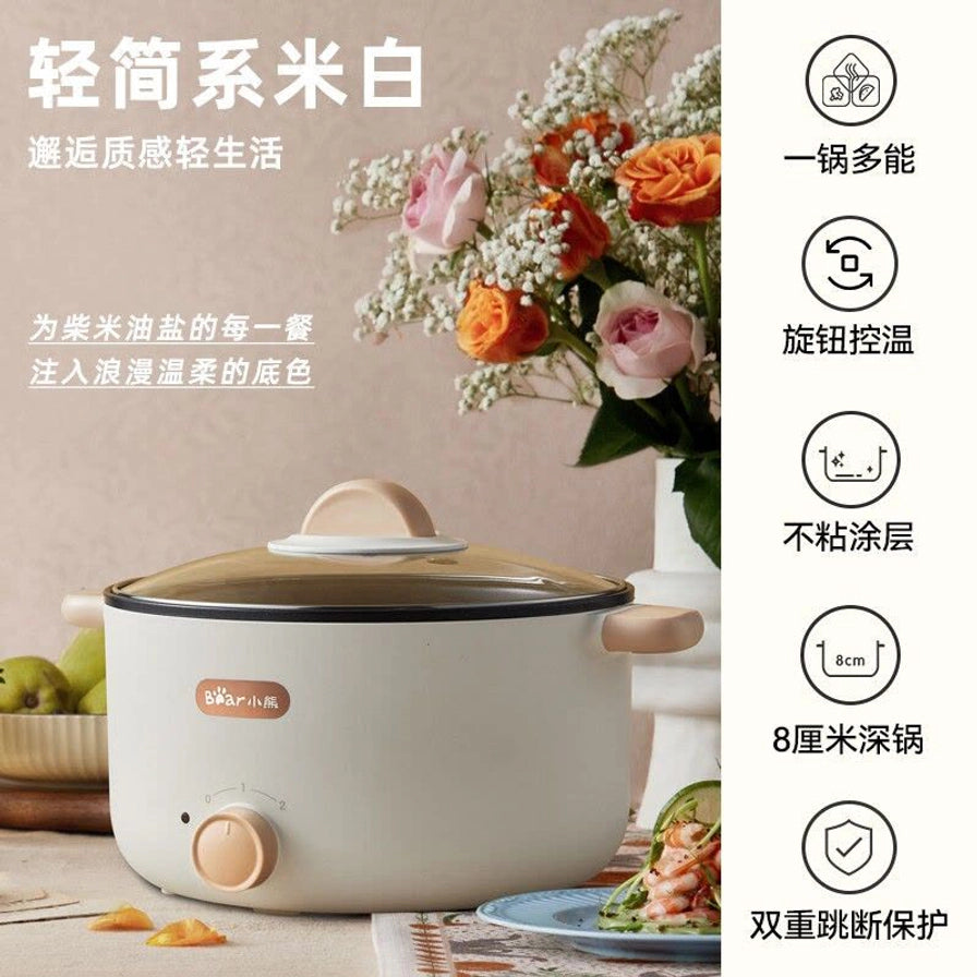 小熊电煮锅在温馨厨房环境中的展示，侧边配有卖点文字说明，包括一锅多能、旋钮控温、不粘涂层等。