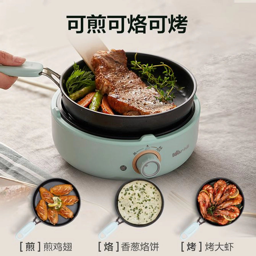 小熊电煮锅使用煎锅煎牛排的近景，配图展示煎鸡翅、烙饼和烤大虾的功能卖点。