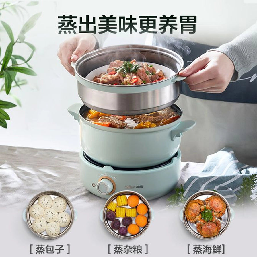 双手端起小熊电煮锅的不锈钢蒸笼，展示上蒸下煮功能，配图展示蒸包子、蒸杂粮和蒸海鲜。