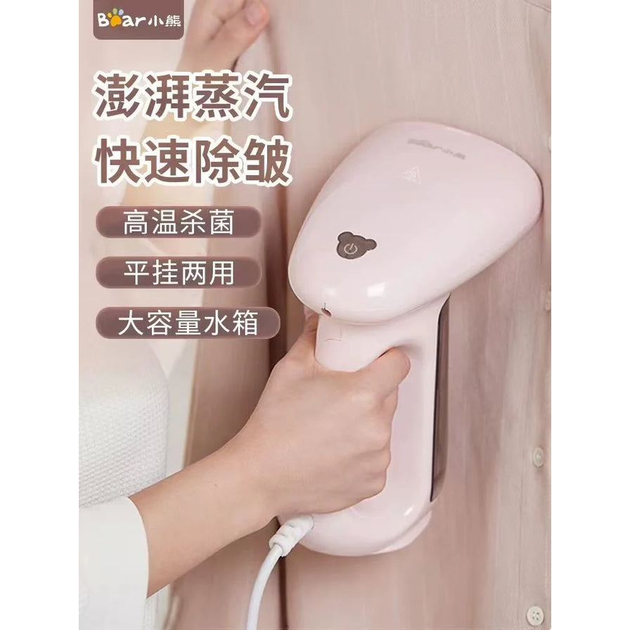 手持小熊粉色挂烫机正在熨烫浅色衬衫，配有澎湃蒸汽、快速除皱等卖点文字。