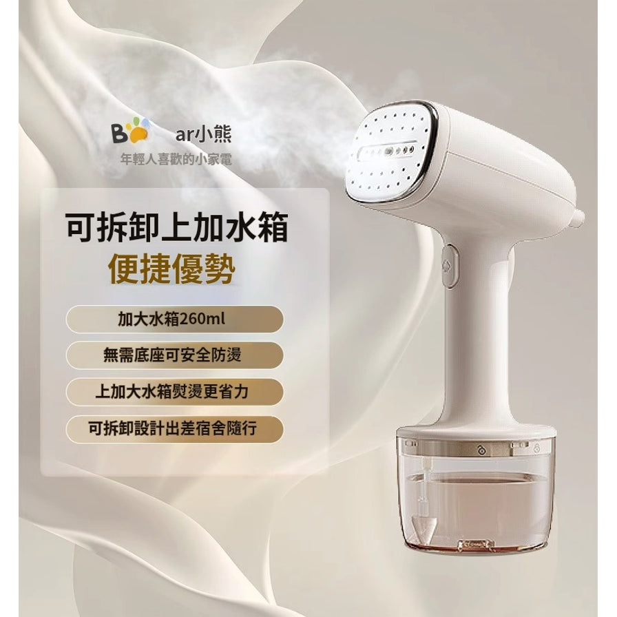 小熊手持挂烫机正在喷射蒸汽，侧边文字介绍其260ml加大水箱及可拆卸设计优势。