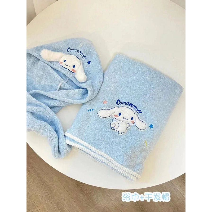摆放在白色桌面上的玉桂狗蓝色浴巾和干发帽两件套，底部带有“浴巾+干发帽”中文字样。