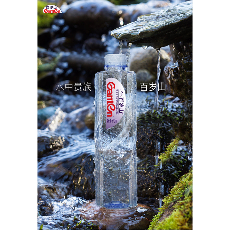 百岁山矿泉水瓶身置于山间溪流泉水背景中，配有“水中贵族 百岁山”文字，展现水源纯净感。