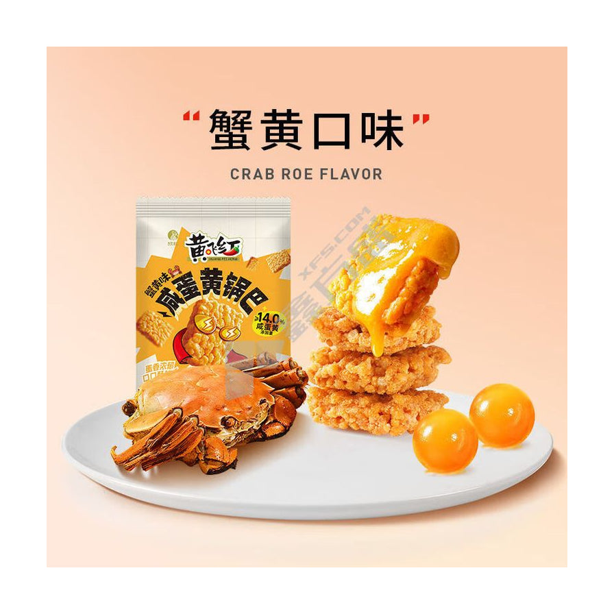 蟹黄口味展示图，白色盘子上摆放着包装袋、淋有酱汁的锅巴堆、一只熟螃蟹和两颗咸蛋黄。