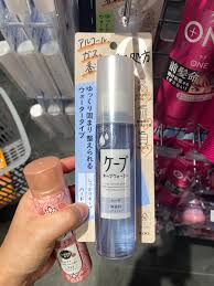 手持花王 Cape 定型喷雾在货架前的实拍场景图，背景可见其他美发产品。