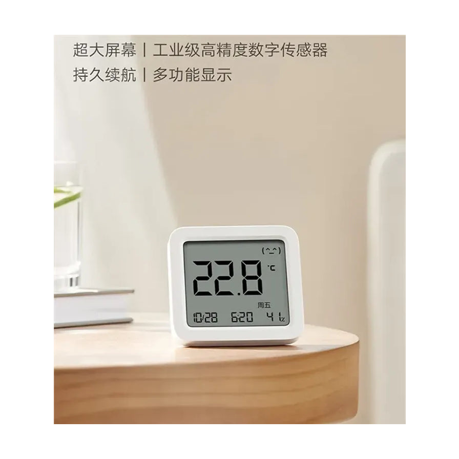 小米米家智能温湿度计3放置在木质桌面上的生活场景，背景为简约居家风格，上方带有超大屏幕和高精度传感器的中文说明。