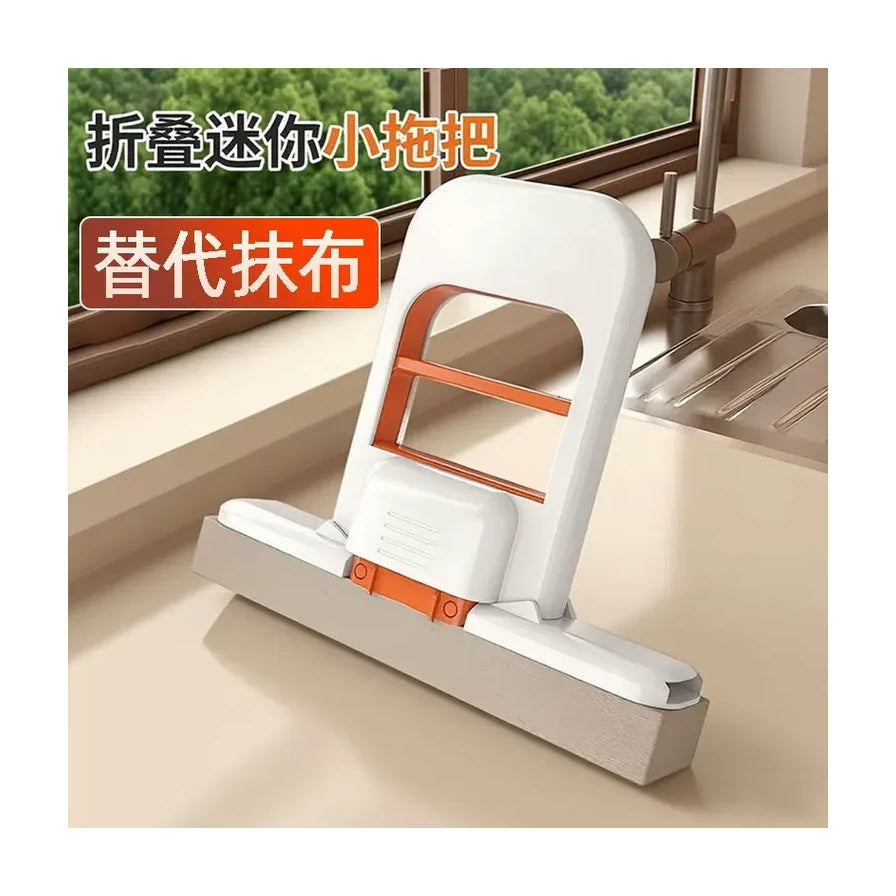 放置在厨房台面上的迷你海绵拖把，背景为水槽和窗户，配有“折叠迷你小拖把，替代抹布”的文字。