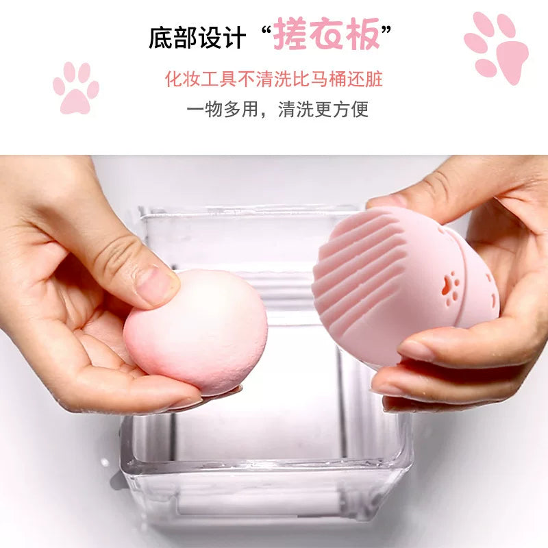 双手展示粉色猫咪收纳盒底部搓衣板纹理与水滴美妆蛋，上方带有中文功能说明文字。
