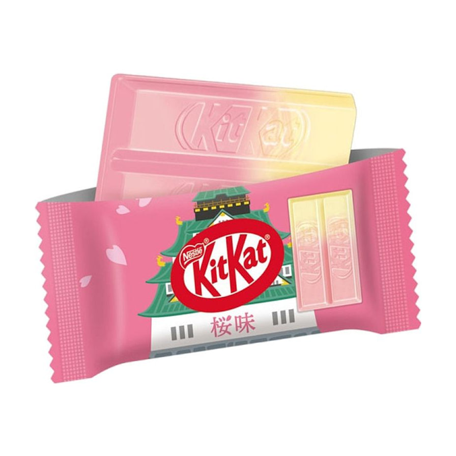 日产雀巢 KitKat 樱花味巧克力威化，粉色渐变包装，印有城堡图案及“樱味”字样，展示内部粉黄双色巧克力。