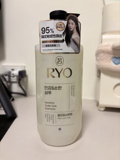 RYO 洗发水实拍图，瓶身顶部贴有含中文和人物肖像的促销贴纸，背景为室内桌面。