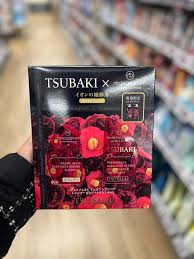 手持 TSUBAKI 黑椿修护洗护套组礼盒在超市货架前的实拍场景图。