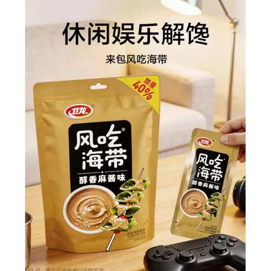 在居家休闲场景中，桌面上摆放着卫龙风吃海带醇香麻酱味包装，背景有游戏手柄，上方配有“休闲娱乐解馋”的文字。