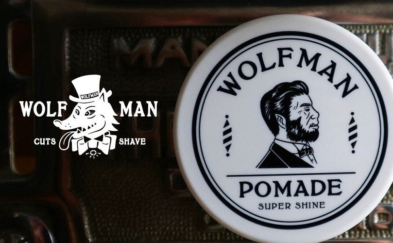 Wolfman 发油产品特写图，白色圆罐置于深色复古背景上，画面左侧叠加有狼头卡通形象及 CUTS SHAVE 英文宣传标识。