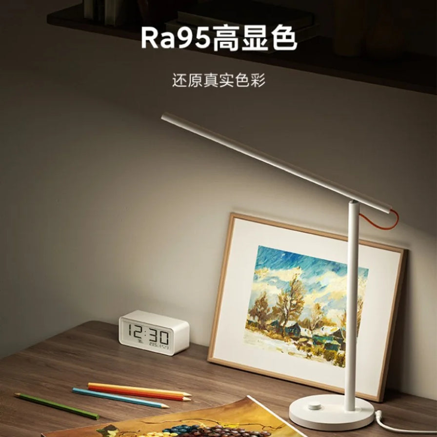 小米米家台灯1S增强版在书桌上的使用场景，光线柔和，上方配有Ra95高显色文字说明。